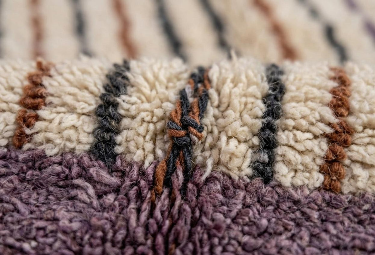 Gros plan sur la laine du tapis berbère Tinzar, poil blanc et lavande noué à la main