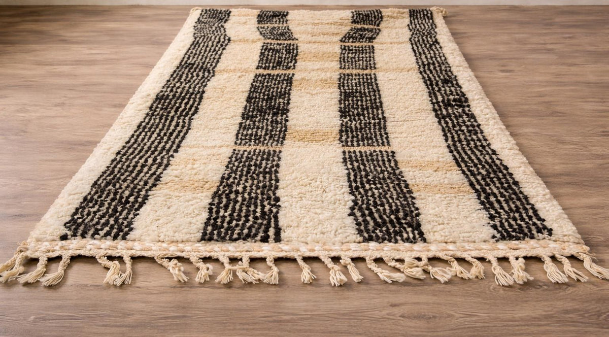 Tapis berbère à rayures blanc et noir Ighed posé au sol vu de côté, noué main au Maroc
