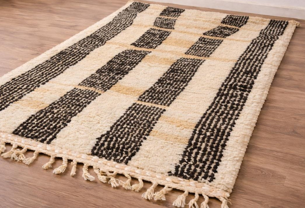 Tapis berbère à rayures blanc et noir Ighed posé au sol vu en biais, noué main au Maroc