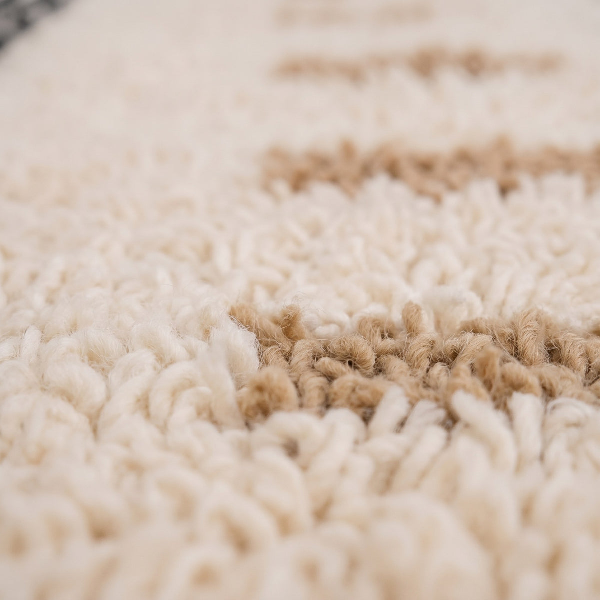 Gros plan sur un motif du tapis berbère Tarzimt, champ à poil long bouclé, fond écru