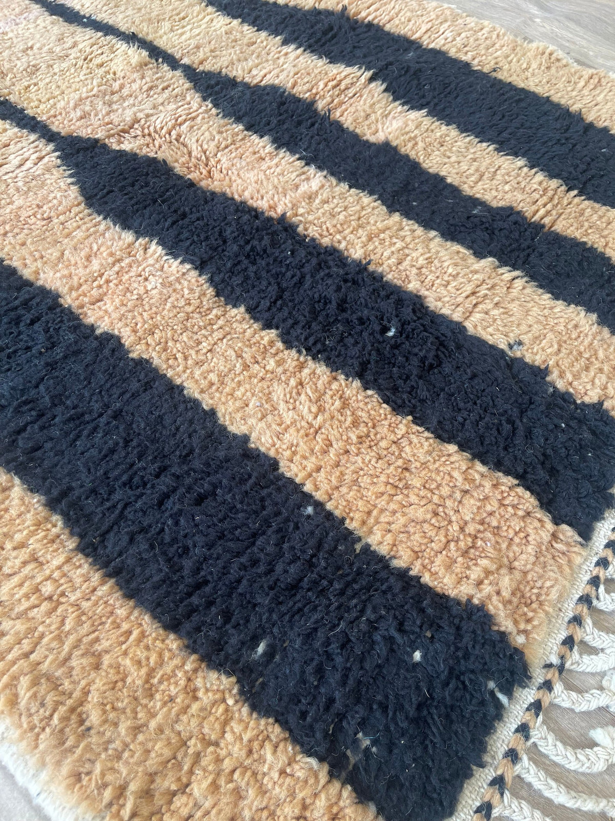 Gros plan sur la laine du tapis berbère Tazroun, laine de mouton au poil long, camel et noire