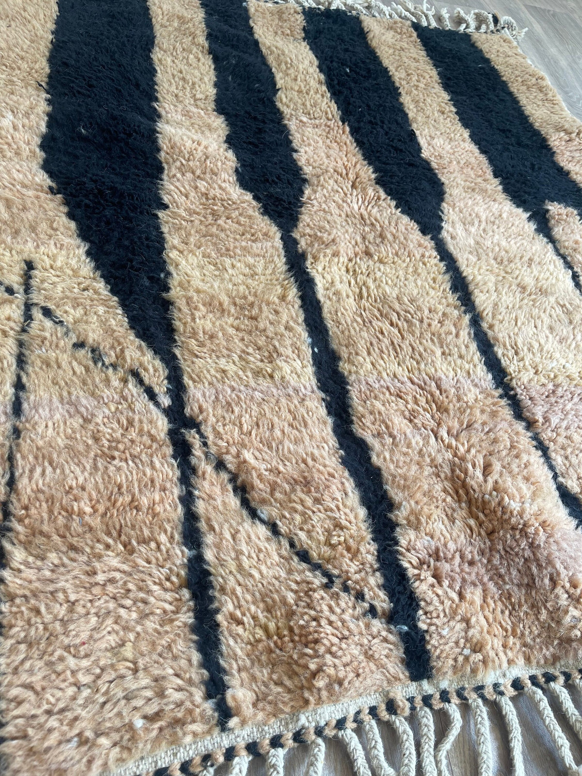 Gros plan sur un détail du tapis berbère Tazroun, poil long et motif camel et noir vus de près