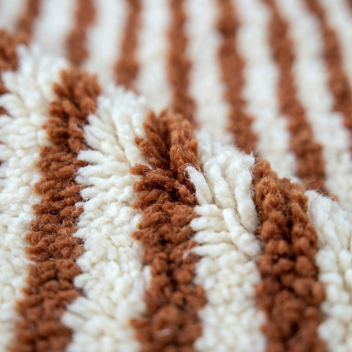 Gros plan sur un motif du tapis berbère Daoura, environ trente fines rayures verticales cognac alternées