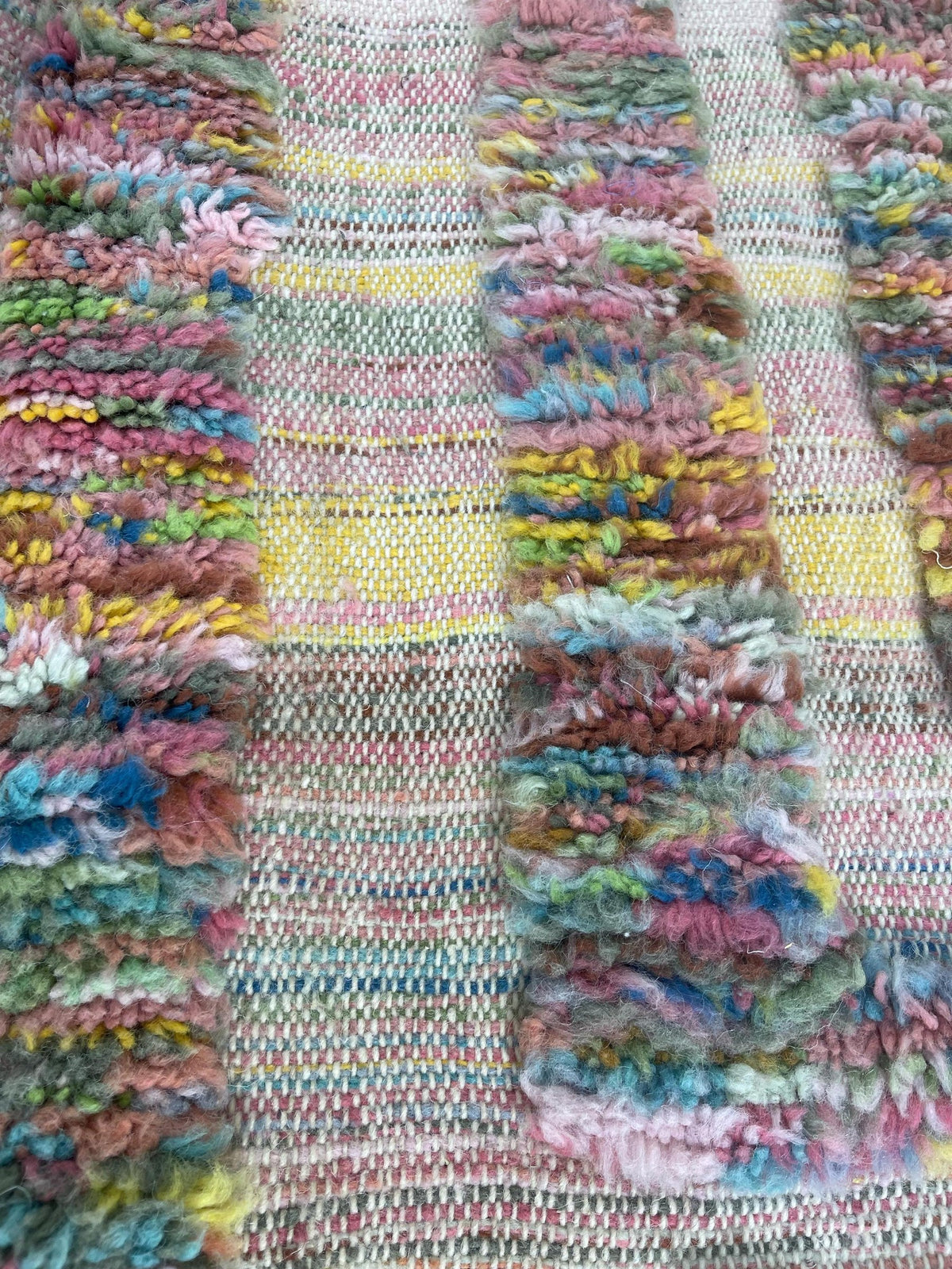 Gros plan sur la laine du tapis berbère Tissa, relief de la laine et du motif à la lumière