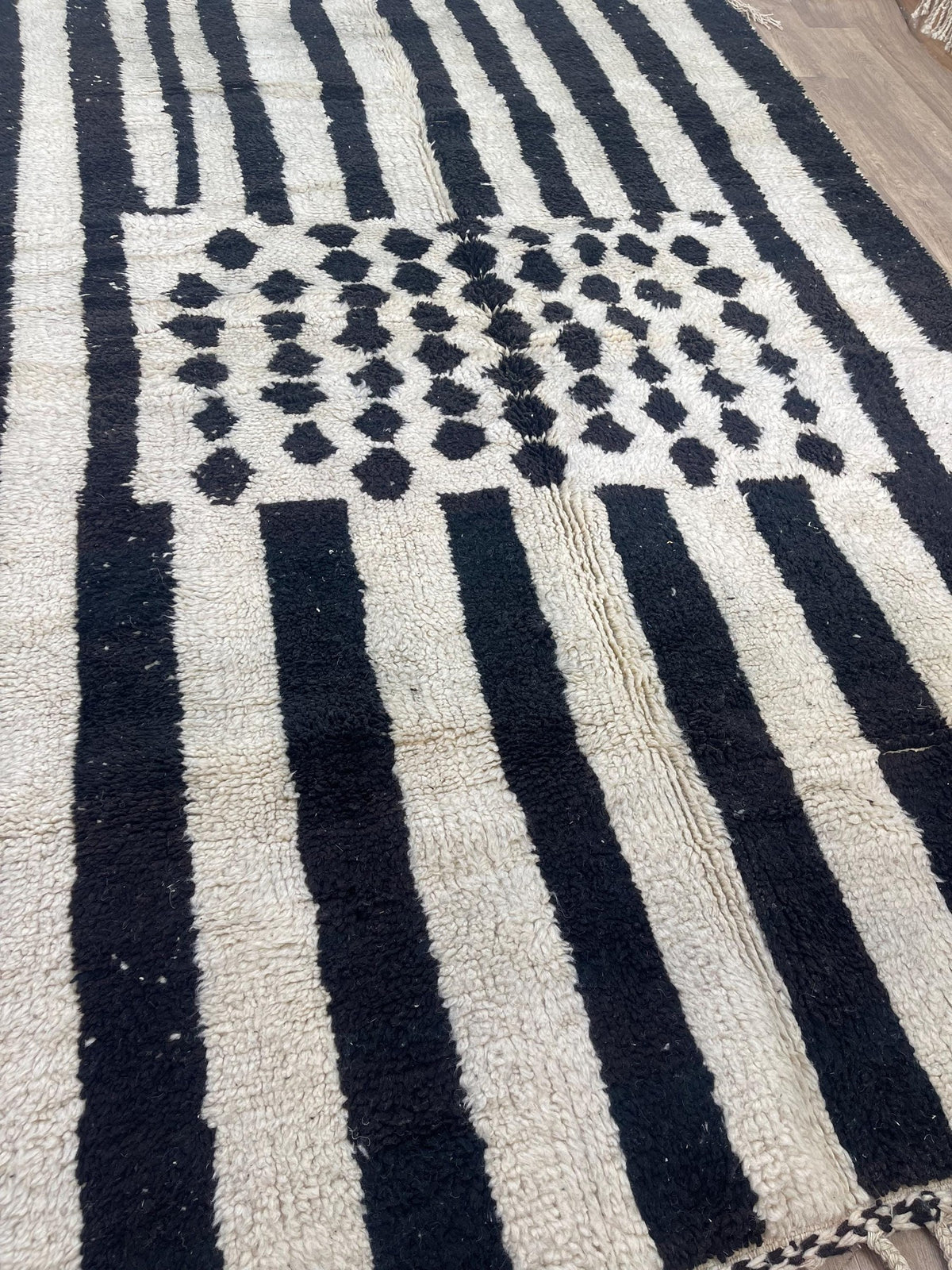 Gros plan sur un détail du tapis berbère Igherm, poil long et motif noir et blanc vus de près
