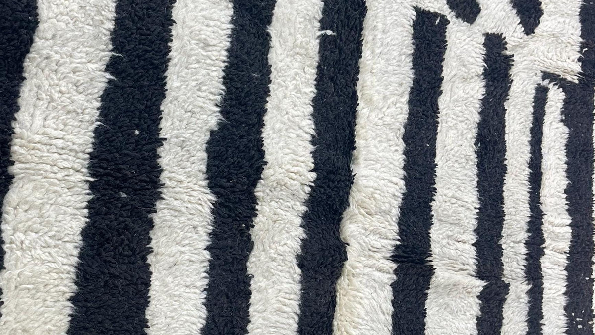 Gros plan sur la laine du tapis berbère Igherm, poil noir et blanc noué à la main