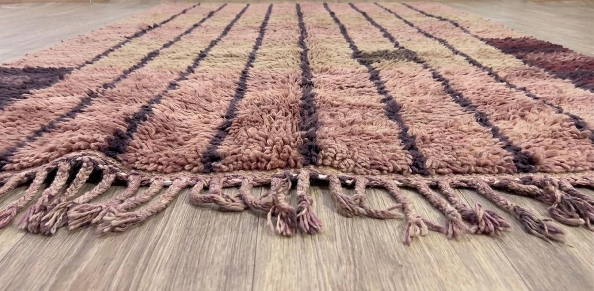 Tapis berbère à rayures rose Tadefi posé au sol vu de côté, noué main au Maroc
