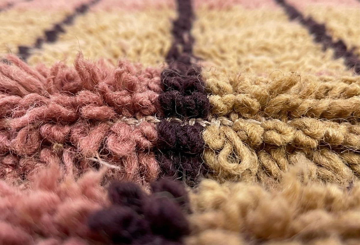 Gros plan sur la laine du tapis berbère Tadefi, poil rose noué à la main