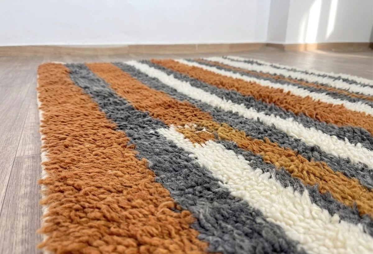 Gros plan sur la laine du tapis berbère Ribab, nœuds serrés et tracé du motif de près
