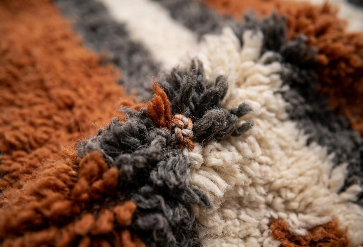 Gros plan sur la laine du tapis berbère Ribab, poil rouille et gris noué à la main