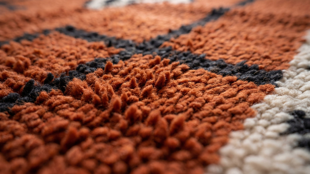 Gros plan sur la laine du tapis berbère Boudinar, poil rouille et noir noué à la main