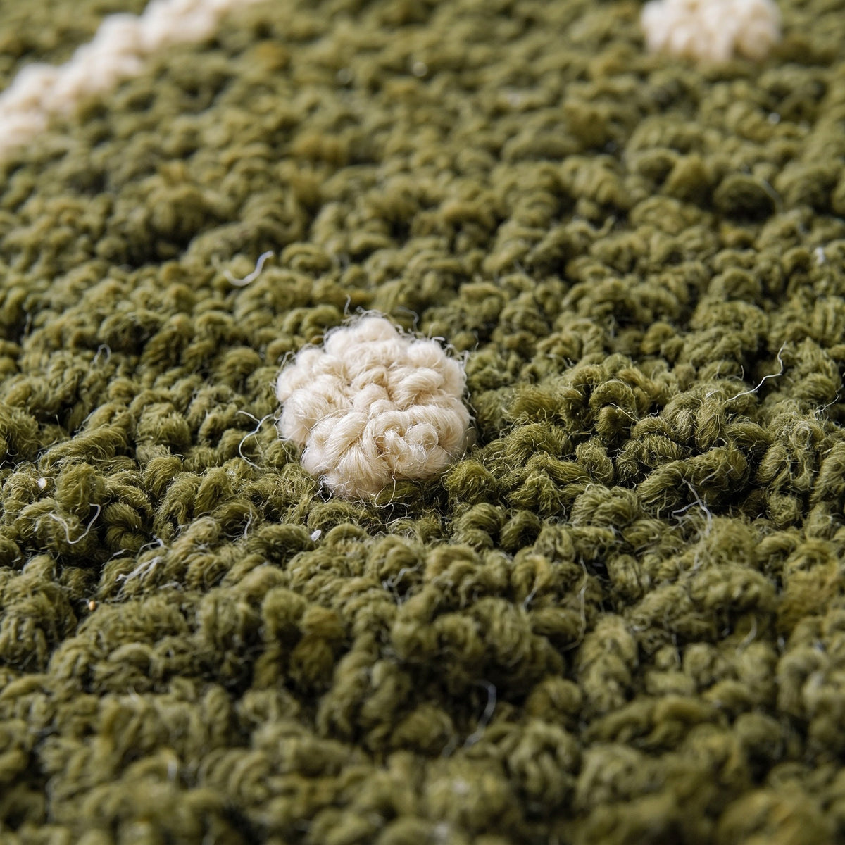 Gros plan sur un motif du tapis berbère Tigumla, champ vert olive à poil bouclé dense