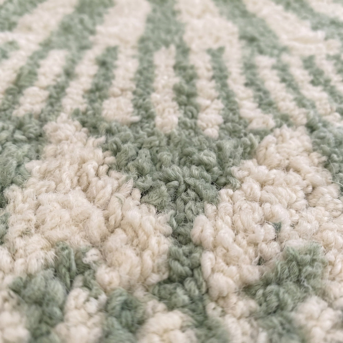 Gros plan sur un motif du tapis berbère Tiddas, rayures verticales vert sauge et écru en haut