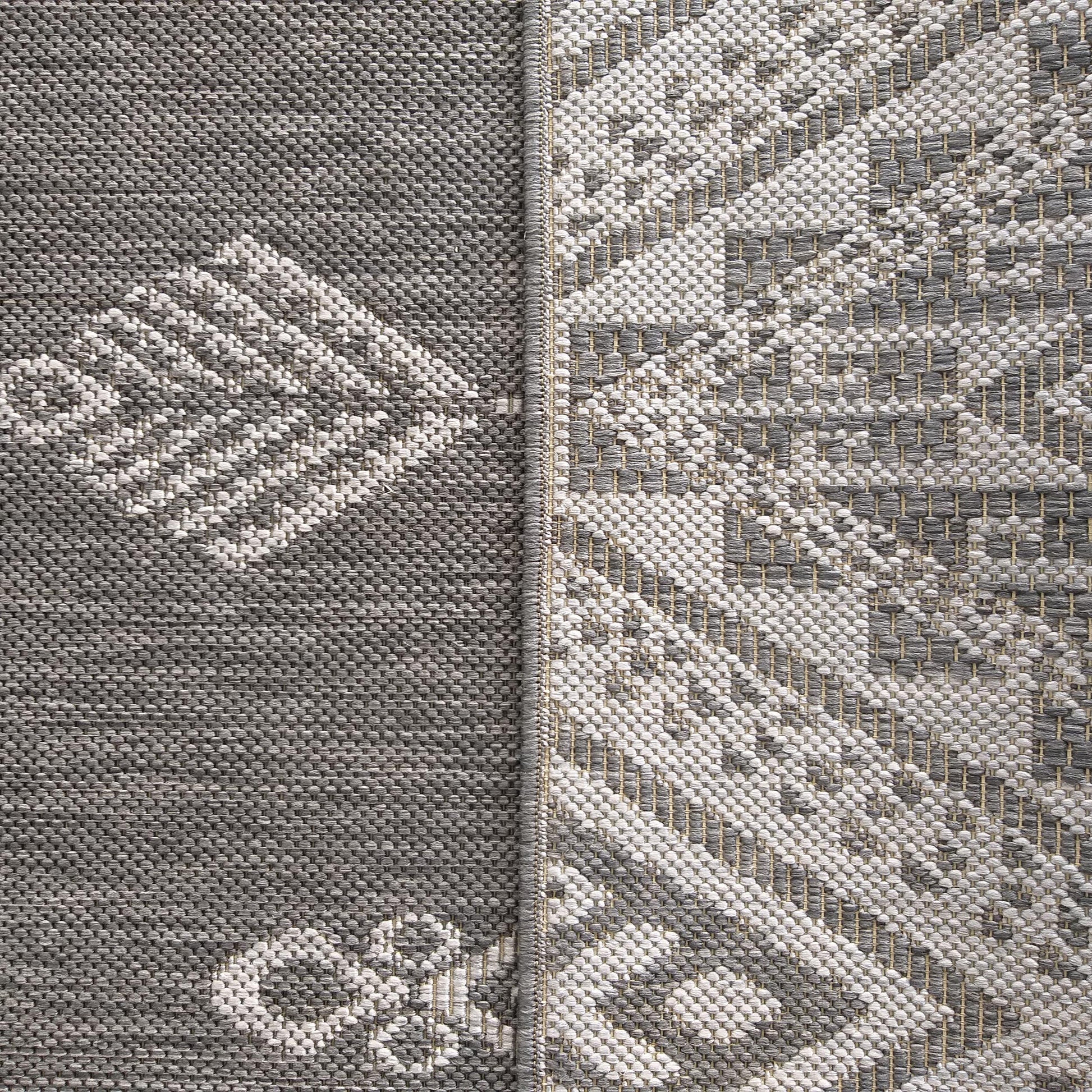 Tapis tissé à motifs géométriques en gris foncé, gris clair, blanc et beige, avec une séparation centrale