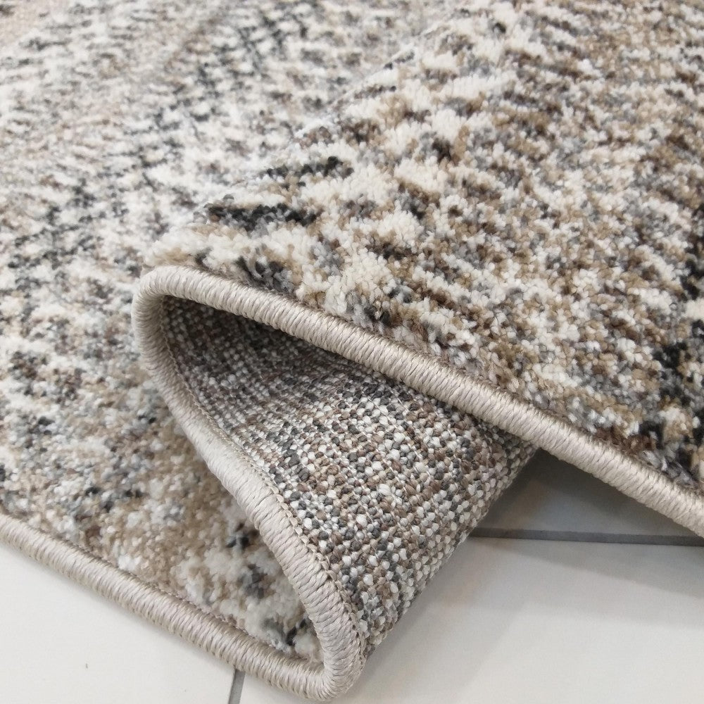 Gros plan sur un tapis texturé roulé, affichant des poils doux aux teintes de beige, blanc, marron et noir aux motifs abstraits