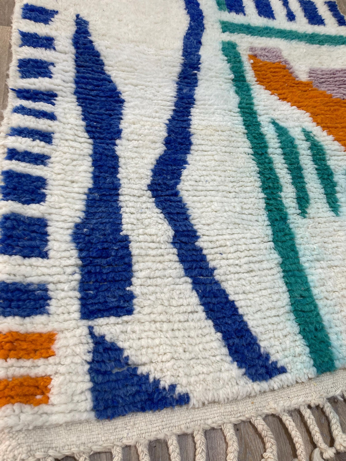 Gros plan sur un détail du tapis berbère Mezgal, poil moyen et motif blanc et bleu vus de près