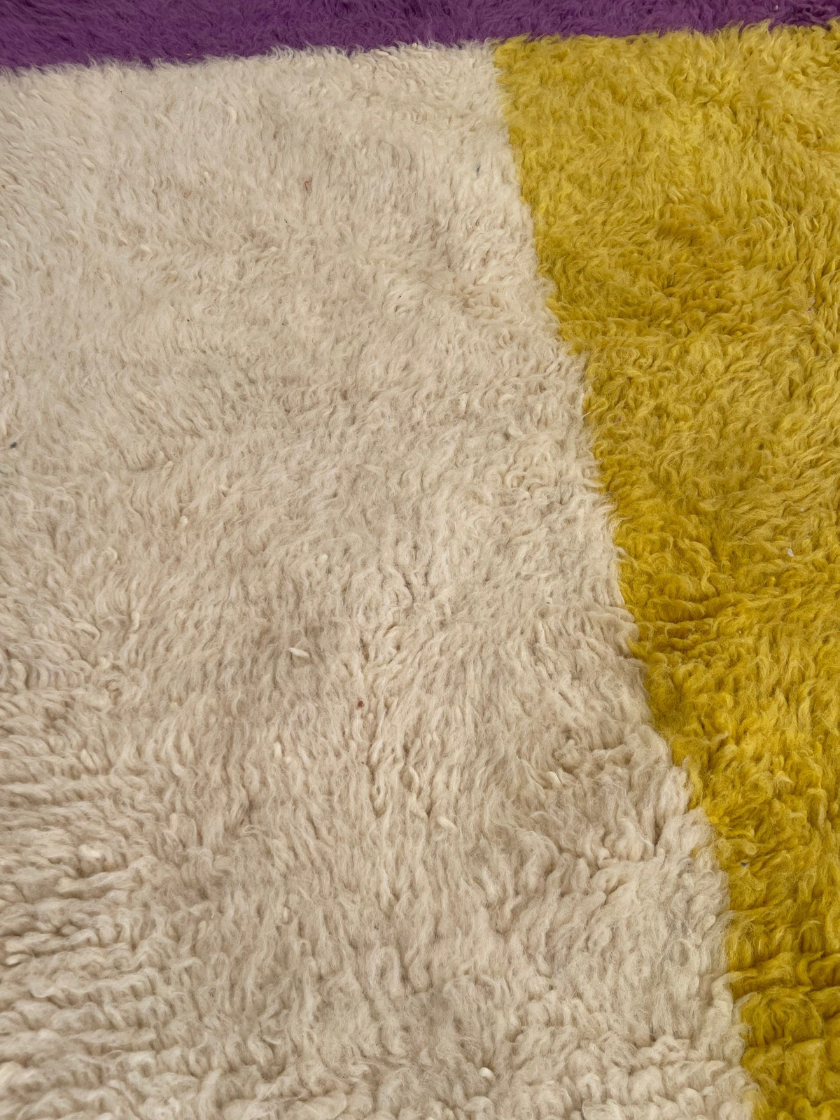 Gros plan sur la laine du tapis berbère Tahala, nœuds serrés et tracé du motif de près