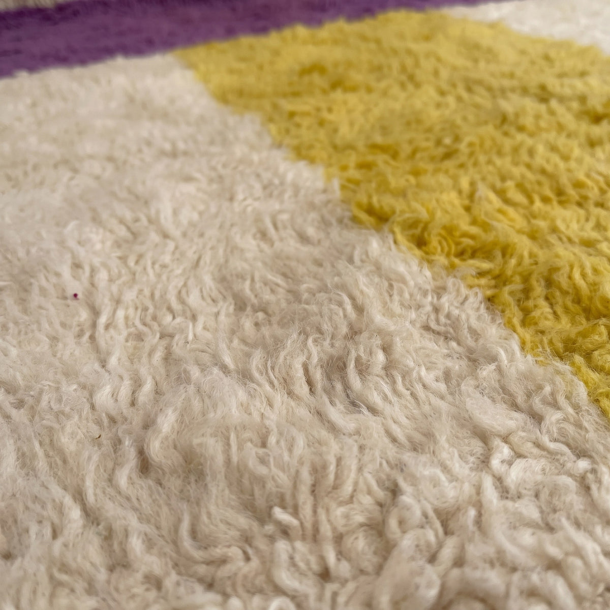 Gros plan sur un motif du tapis berbère Tahala, fond écru, une large bande jaune verticale