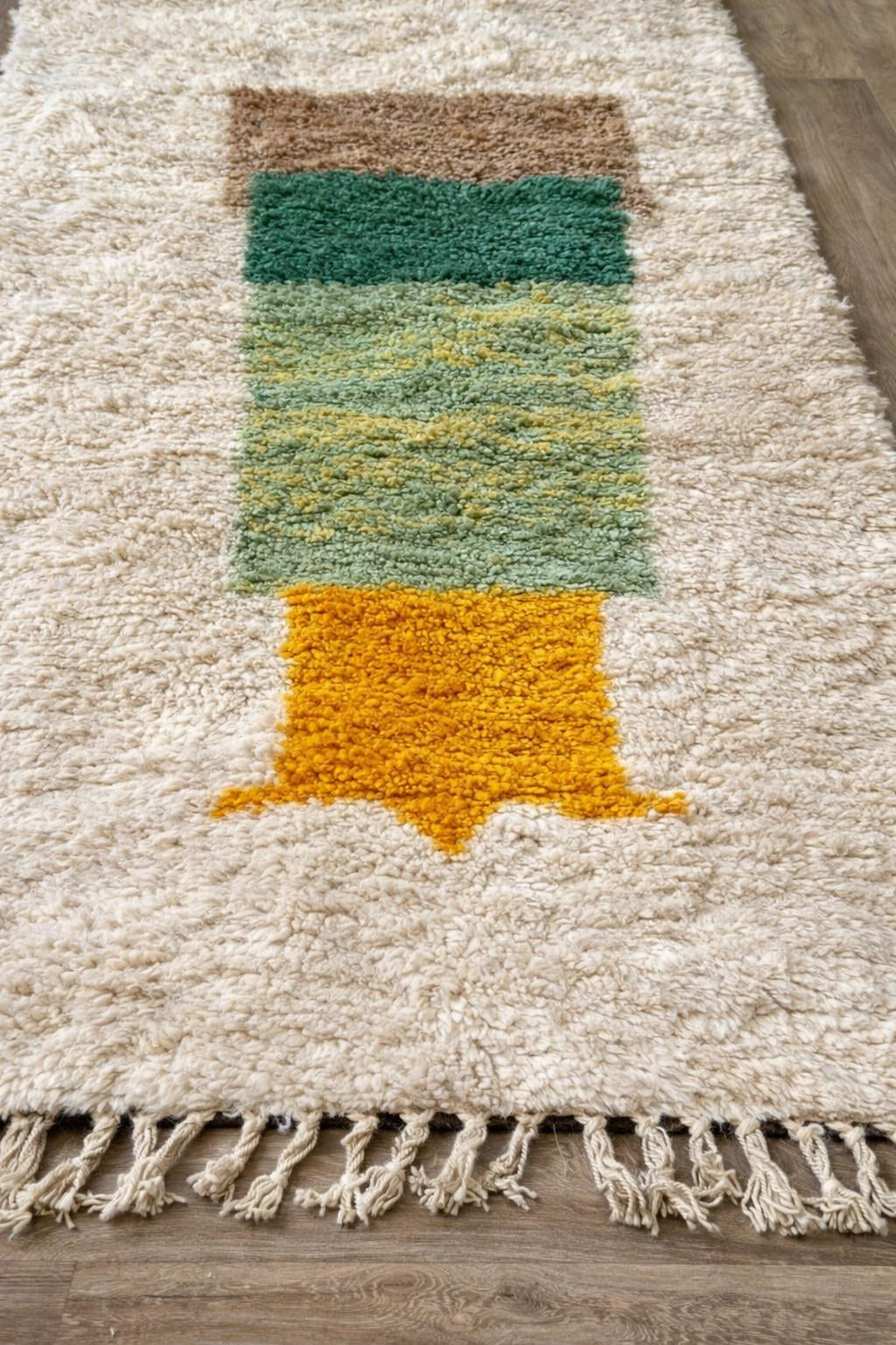 Gros plan sur un détail du tapis berbère Tigalwa, poil long et motif blanc et vert vus de près