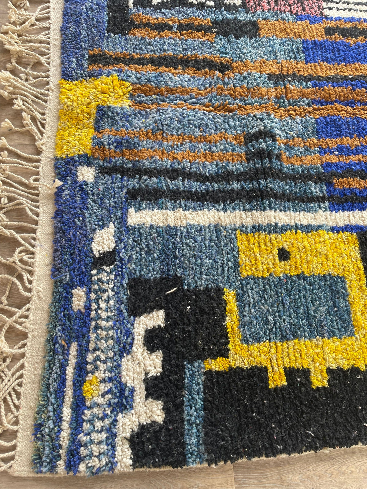 Gros plan sur le coin relevé du tapis berbère Marchica, épaisseur du poil moyen et dos tissé à la main