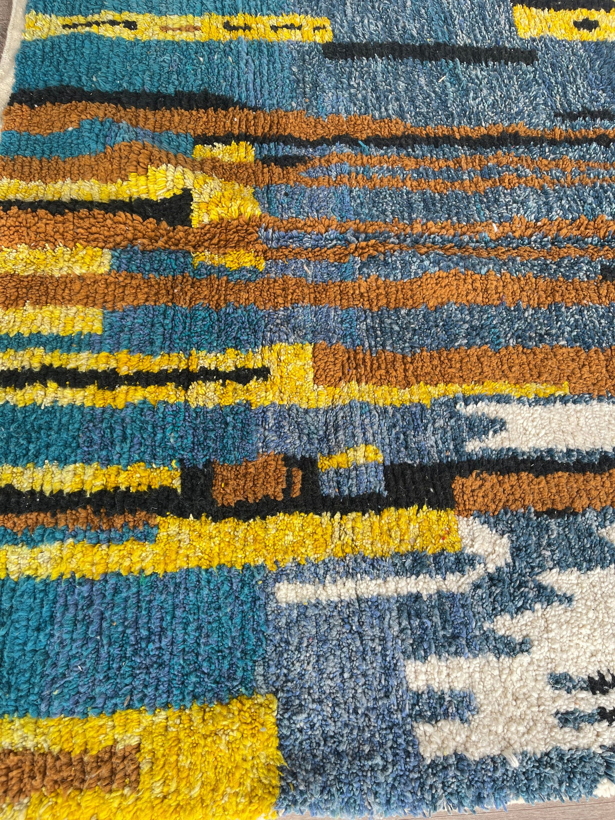 Gros plan sur la laine du tapis berbère Marchica, laine de mouton au poil moyen, bleue et jaune