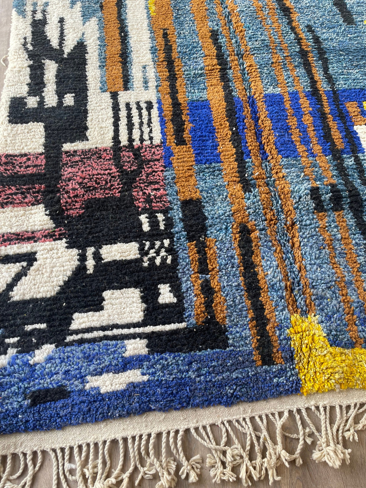 Gros plan sur un détail du tapis berbère Marchica, poil moyen et motif bleu et jaune vus de près