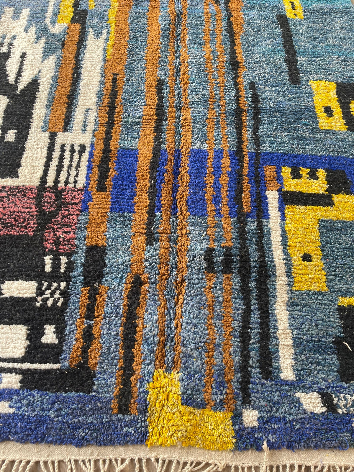 Gros plan sur un détail du tapis berbère Marchica, poil moyen et motif bleu et jaune vus de près, vue 4
