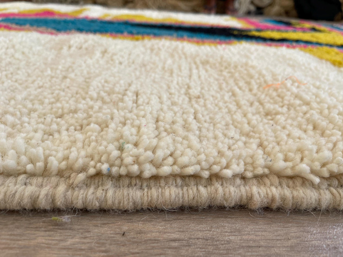 Gros plan sur la laine du tapis berbère Dourzal, laine de mouton au poil moyen, fuchsia et bleue