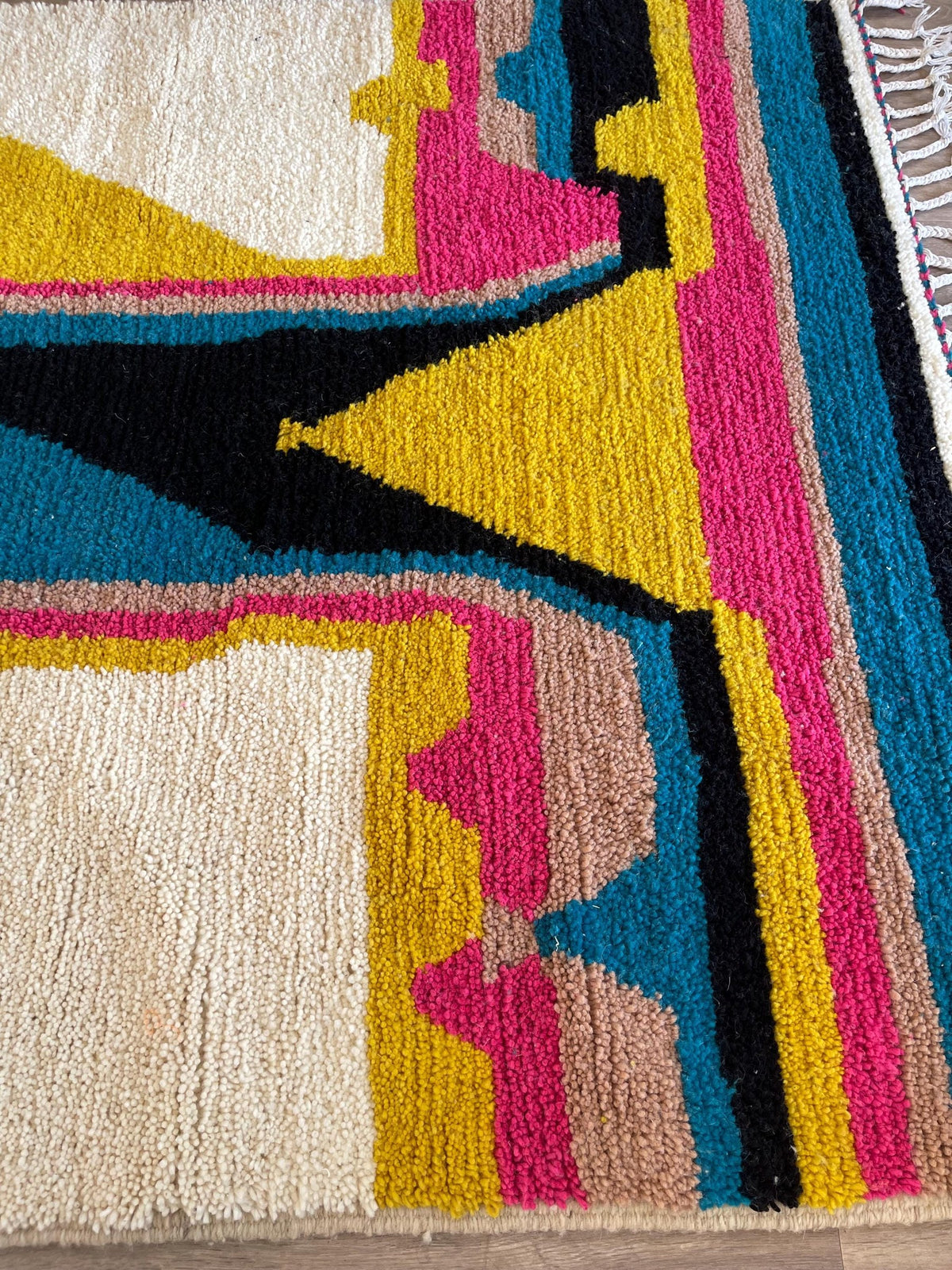 Gros plan sur un détail du tapis berbère Dourzal, poil moyen et motif fuchsia et bleu vus de près