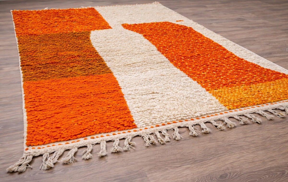 Amadal colourful Berber rug in orange and white, on the floor, seen from the side at an angle, hand-knotted in Morocco
