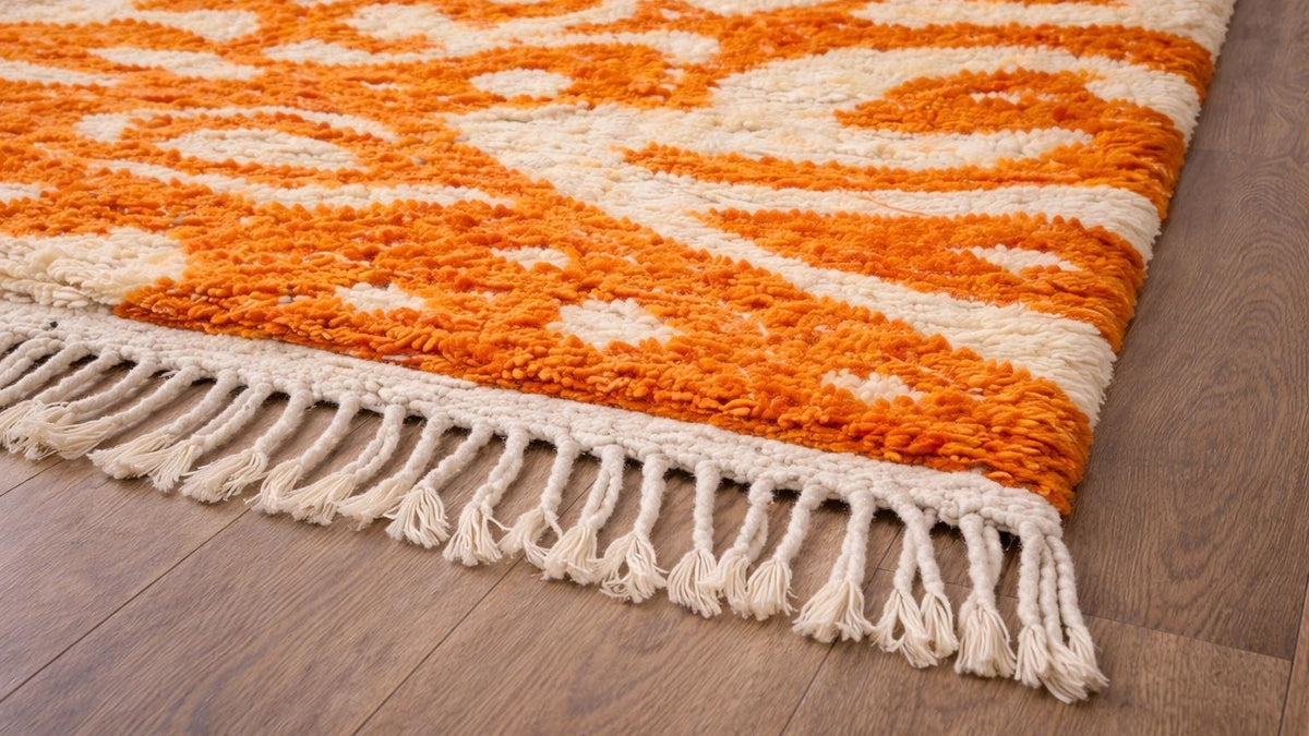 Gros plan sur la laine du tapis berbère Todgha, poil orange et blanc noué à la main
