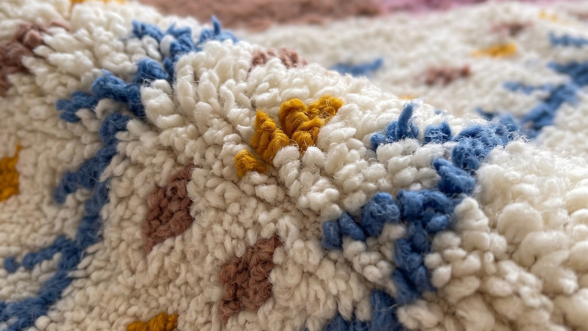 Gros plan sur la laine du tapis berbère Tinejdad, poil rose et orange noué à la main