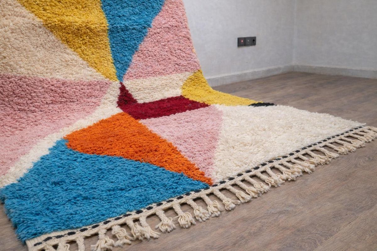 Gros plan sur un détail du tapis berbère Tilelli, poil long et motif rose et turquoise vus de près