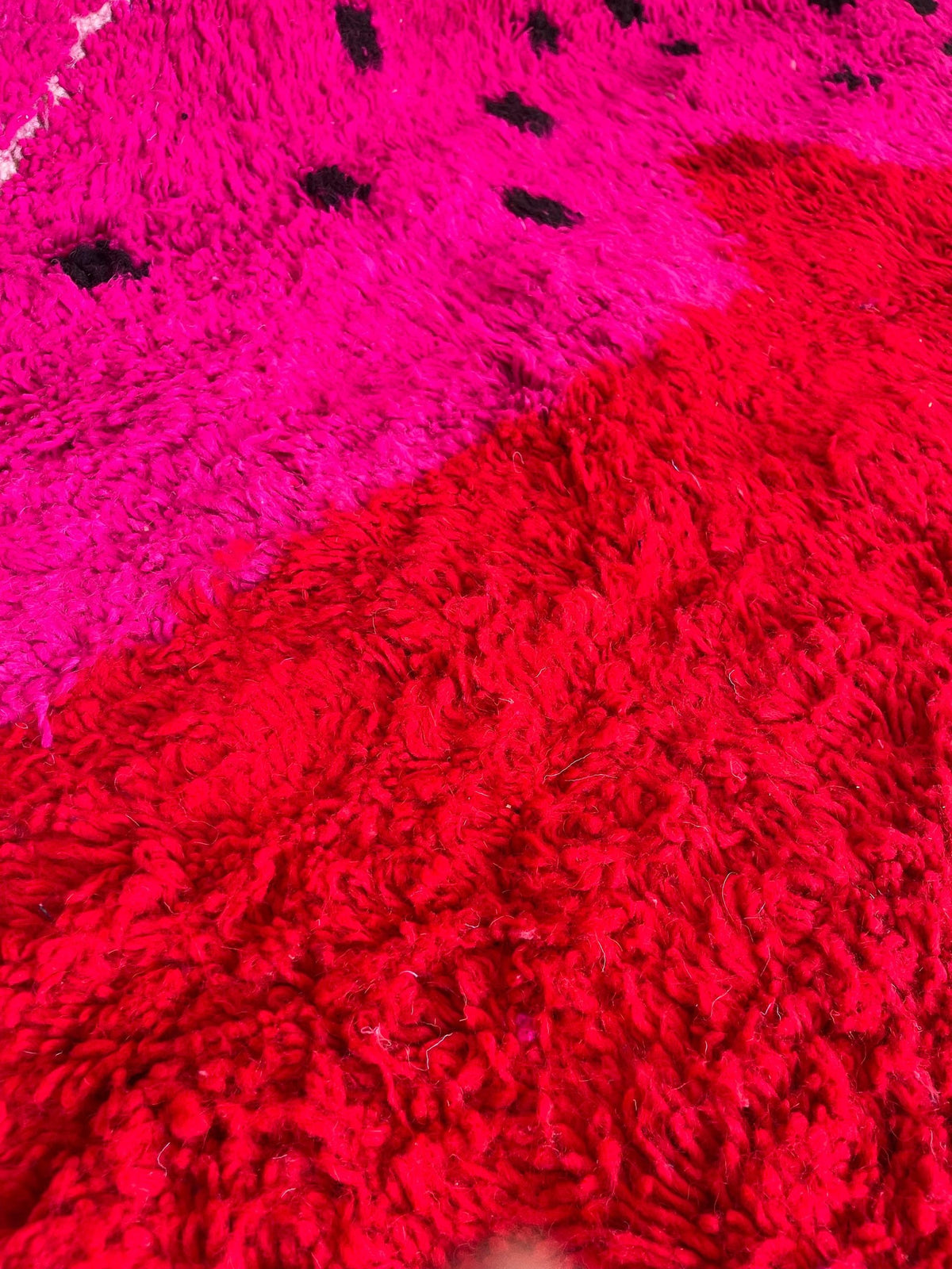 Gros plan sur la laine du tapis berbère Iriki, laine de mouton au poil long, rose fuchsia