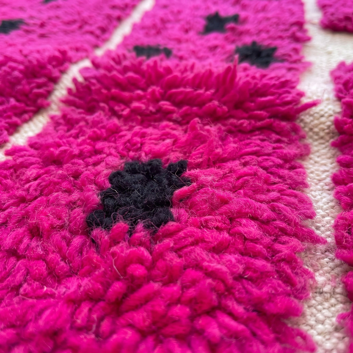 Gros plan sur un motif du tapis berbère Iriki, champ rose fuchsia à poil long