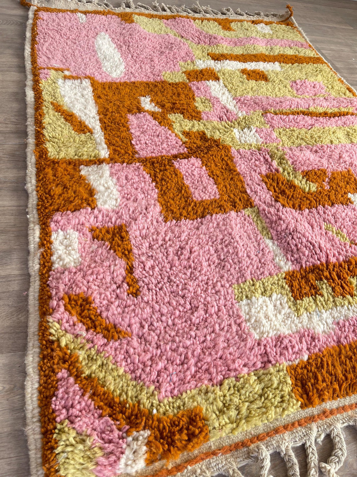 Tapis berbère coloré rose Skoura posé au sol vu de côté, noué main au Maroc