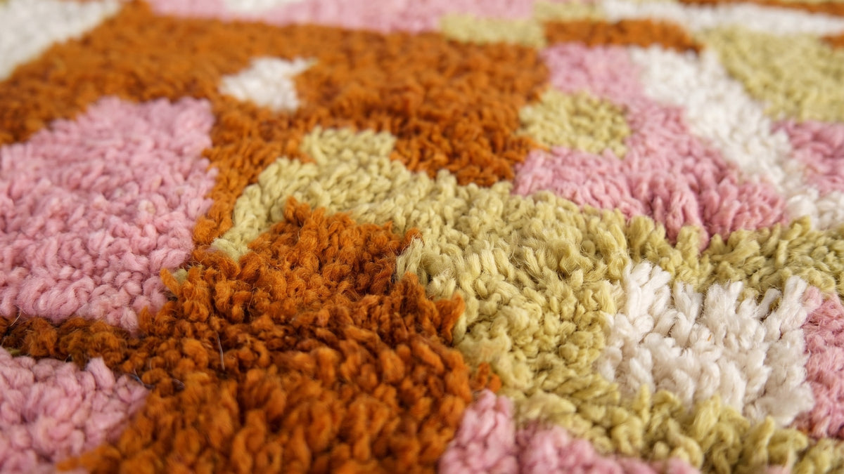 Gros plan sur la laine du tapis berbère Skoura, poil rose noué à la main