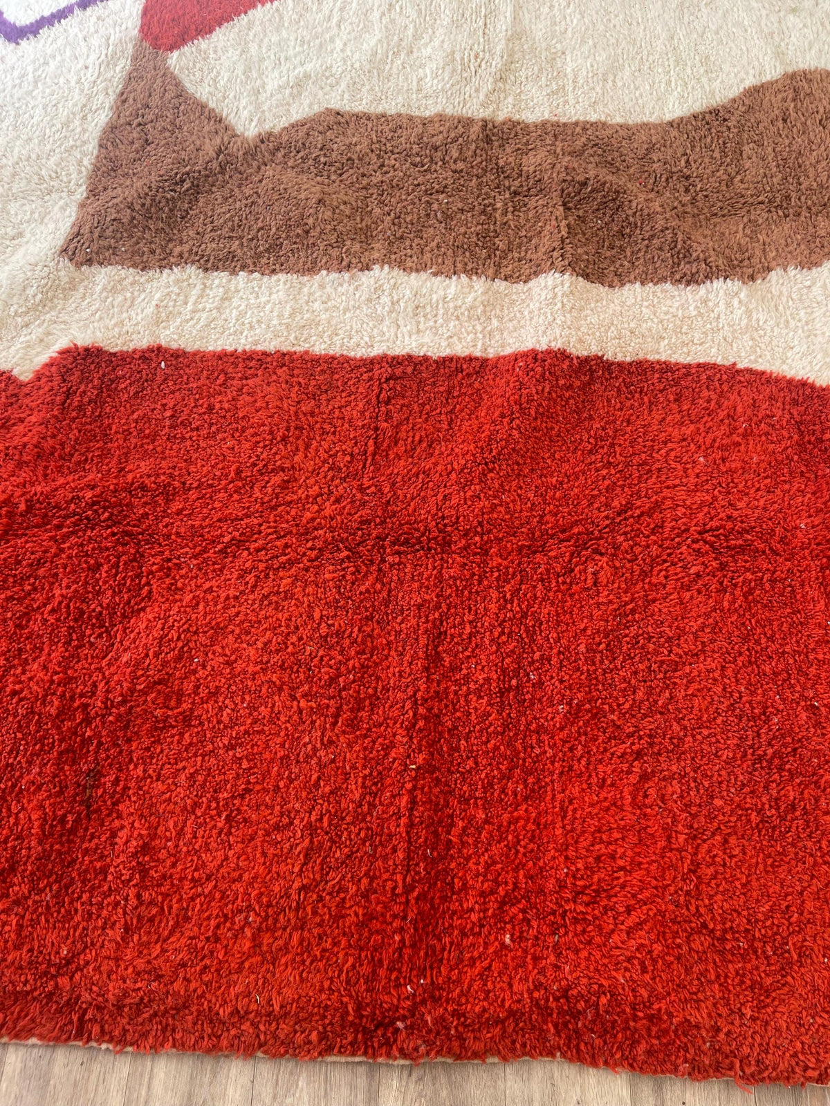 Gros plan sur un détail du tapis berbère Boudnib, poil long et motif rouge et blanc vus de près