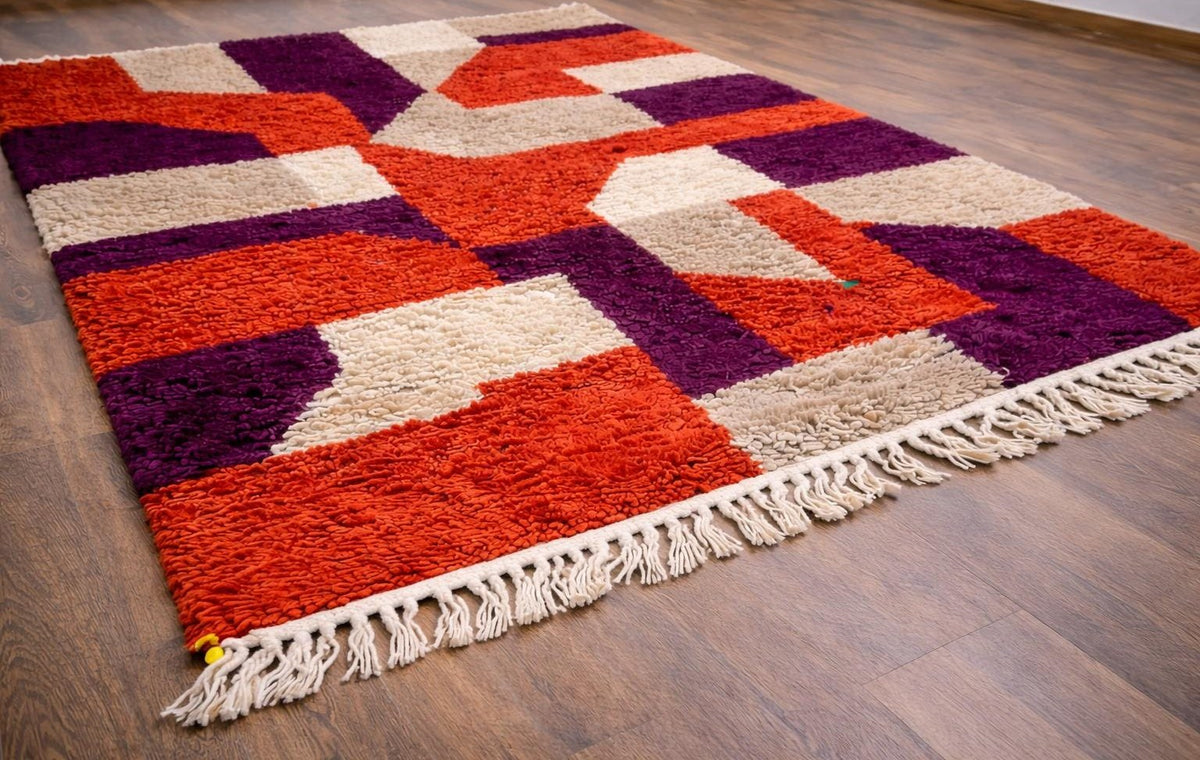 Tapis berbère coloré rouge et violet Alnif posé au sol vu de côté, noué main au Maroc