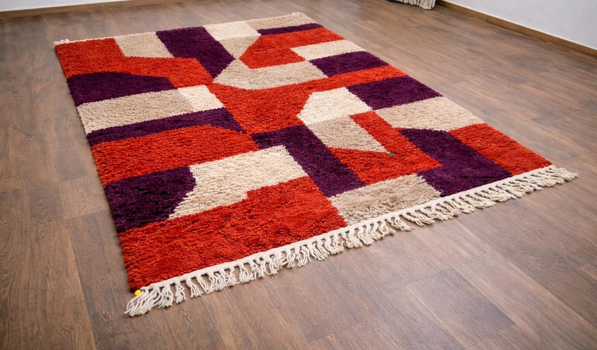 Tapis berbère coloré rouge et violet Alnif posé au sol vu en biais, noué main au Maroc