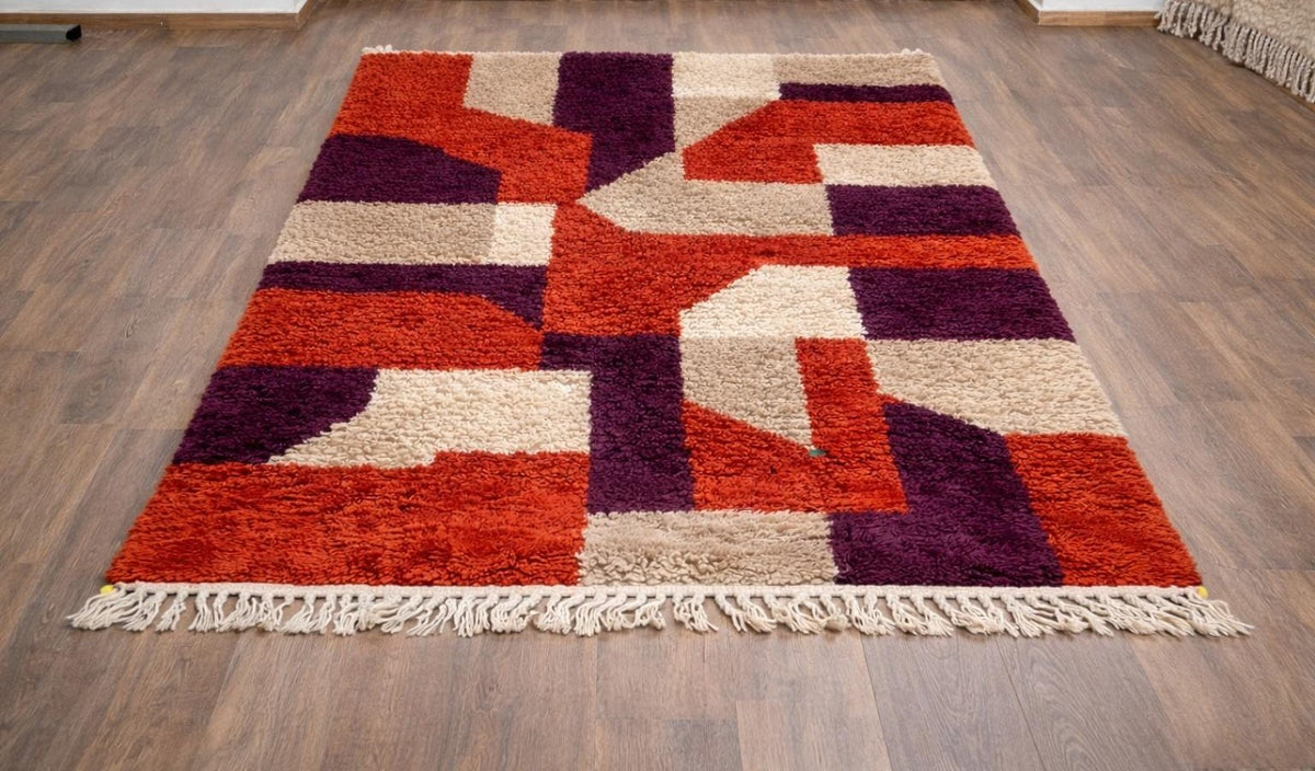 Tapis berbère coloré rouge et violet Alnif posé au sol vu de trois quarts, noué main au Maroc