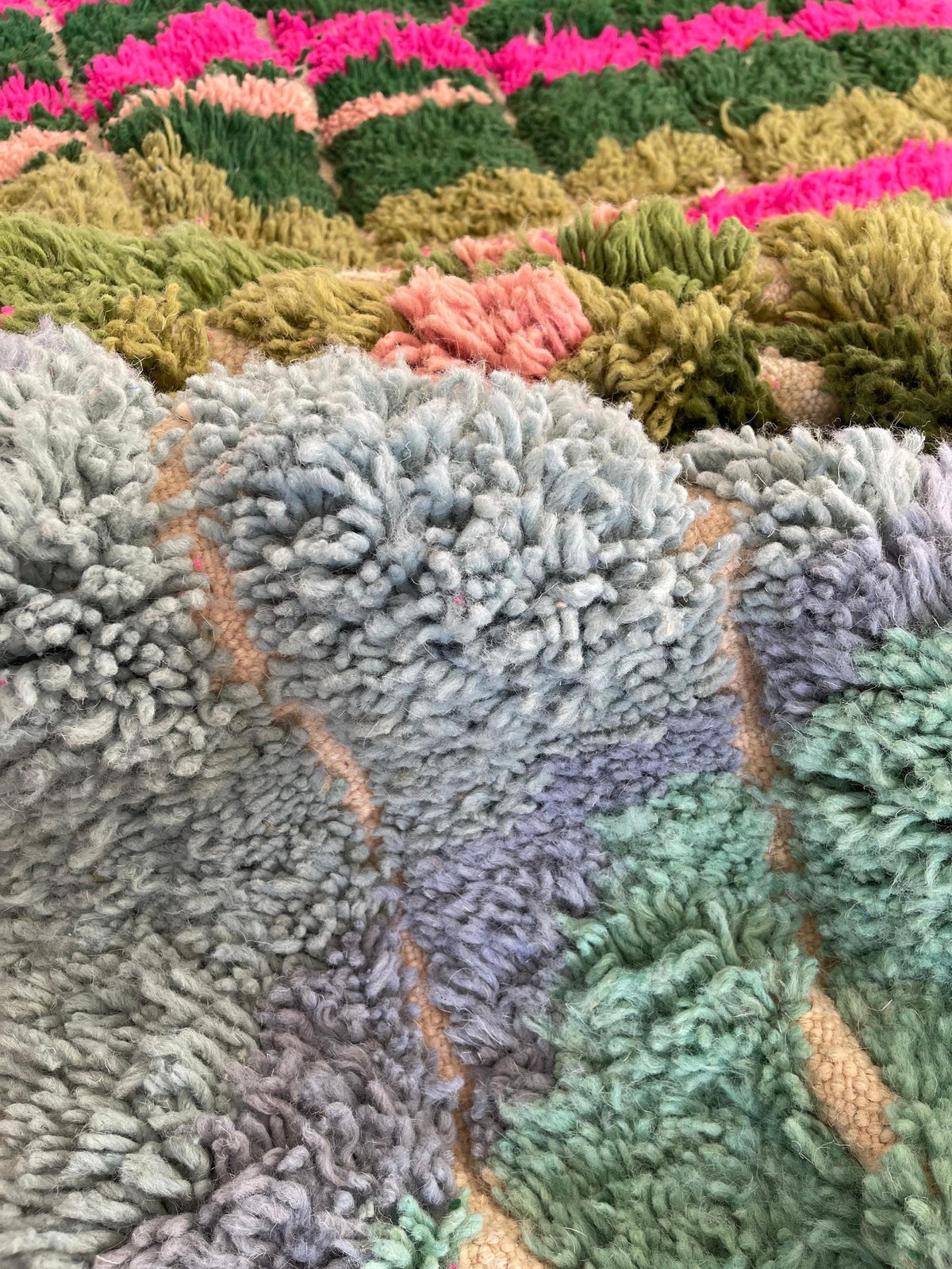 Gros plan sur la laine du tapis berbère Sefrou, laine de mouton au poil long, verte et rose