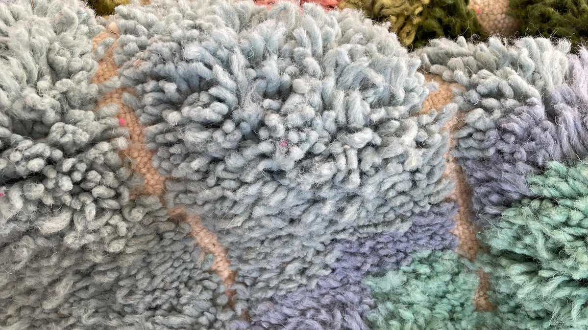 Gros plan sur la laine du tapis berbère Sefrou, poil vert et rose noué à la main