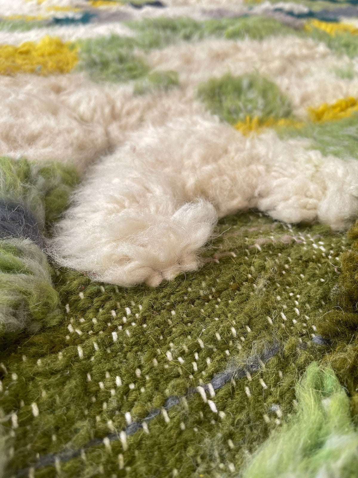 Gros plan sur la laine du tapis berbère Aoufous, nœuds serrés et tracé du motif de près