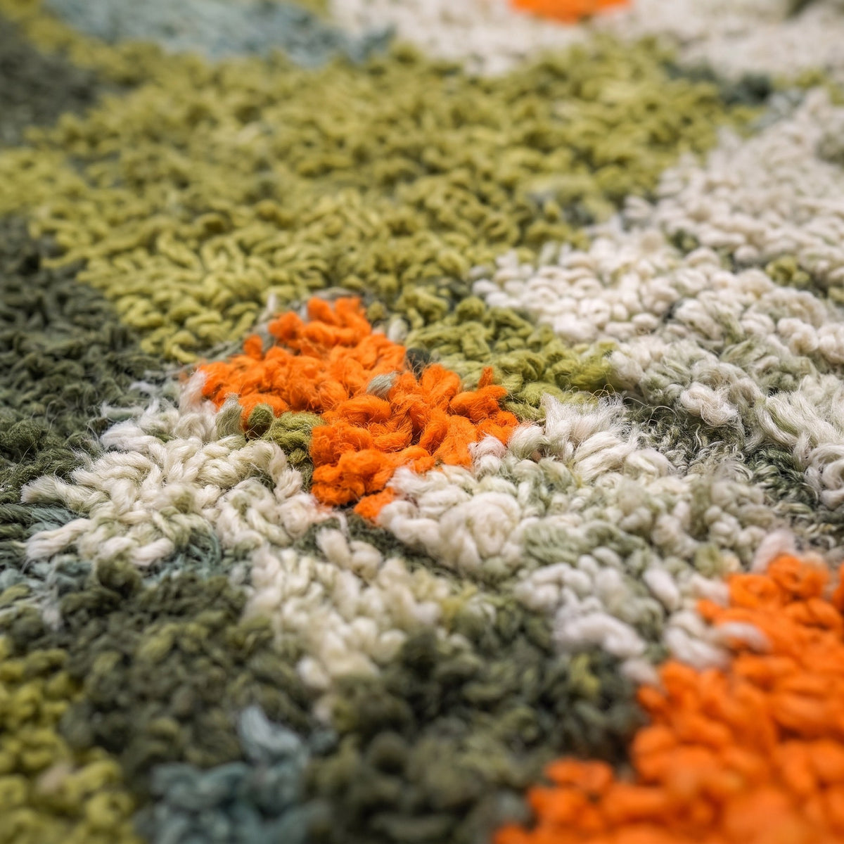 Gros plan sur un motif du tapis berbère Ounagha, mosaïque de carrés et rectangles vert olive