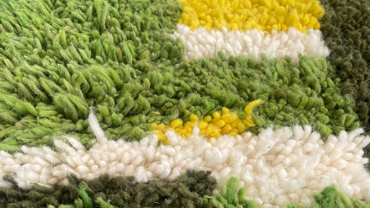 Gros plan sur la laine du tapis berbère Zegzel, poil vert noué à la main