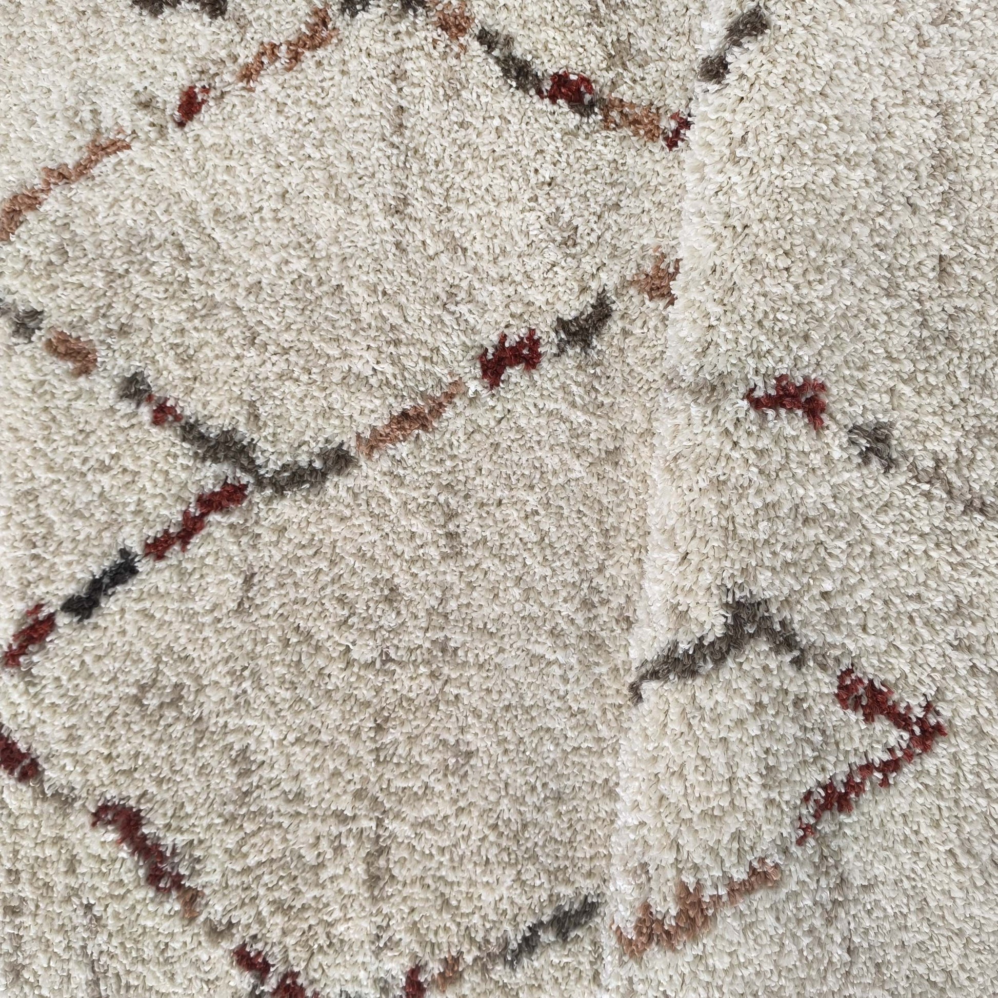 Tapis à poils longs crème avec des motifs de lignes obliques irrégulières et de losanges en marron, gris foncé et bordeaux