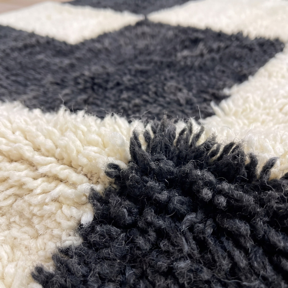 Gros plan sur un motif du tapis berbère Bani, champ à poil long en damier irrégulier noir