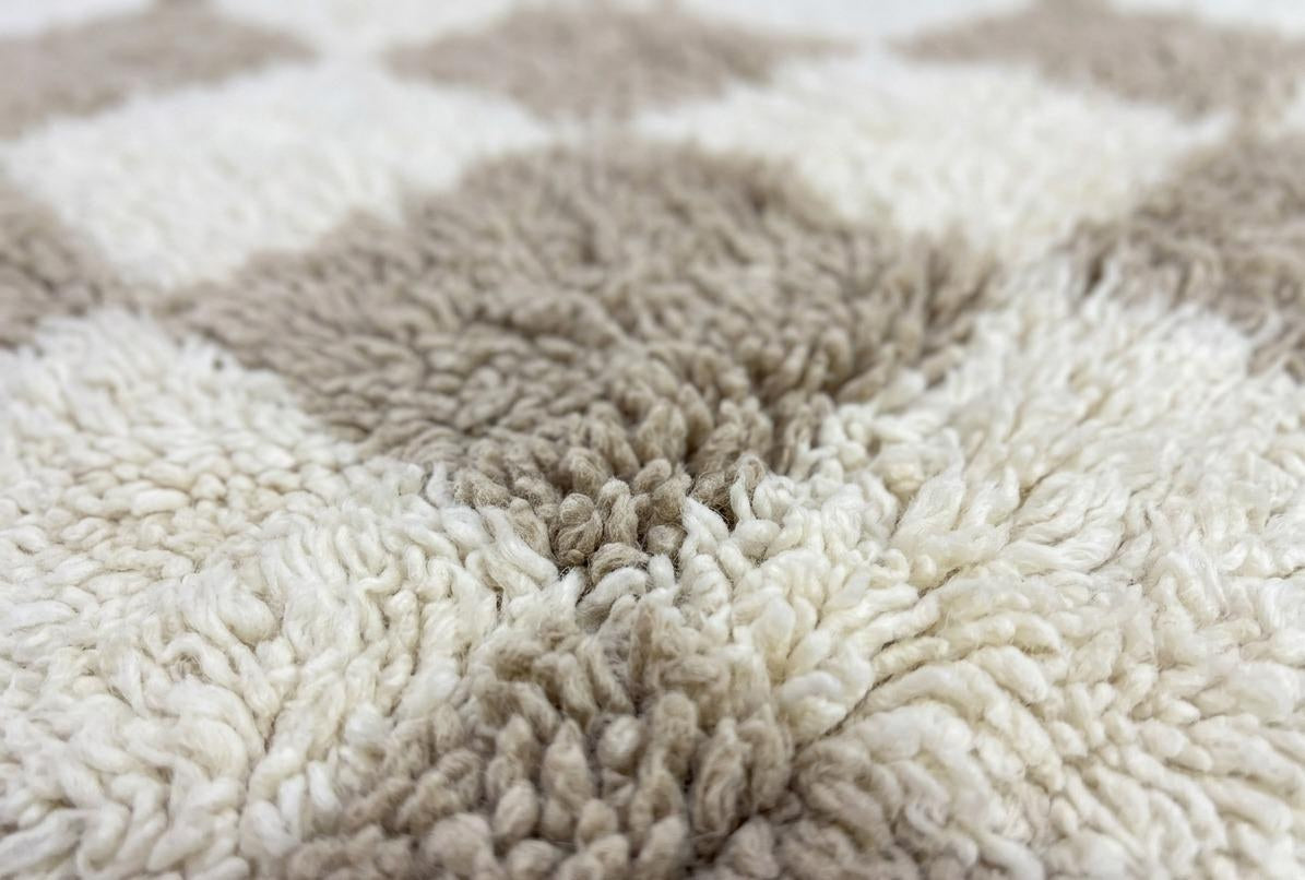 Gros plan sur la laine du tapis berbère Borzan, poil beige et blanc noué à la main