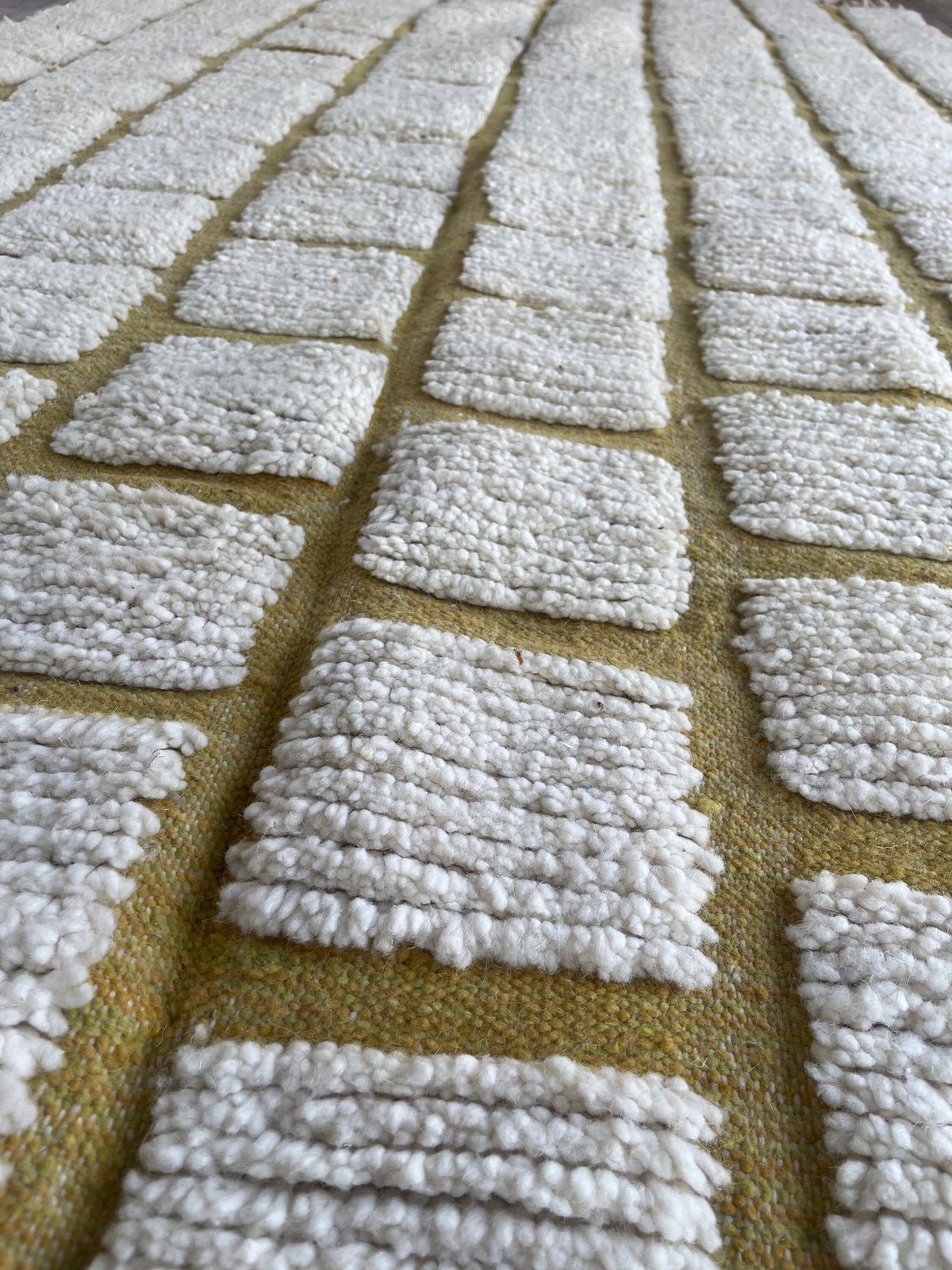 Gros plan sur la laine du tapis berbère Igoudar, nœuds serrés et tracé du motif de près